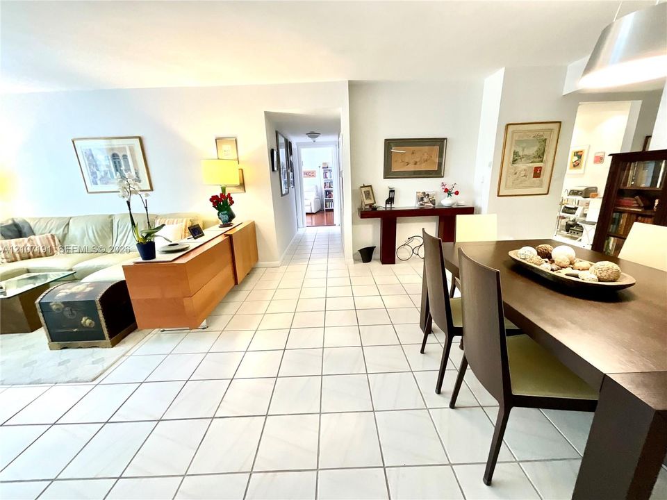 Open-concept floor plan featuring large-format ceramic tile flooring, neutral wall finishes, and a modern brushed-metal pendant light fixture