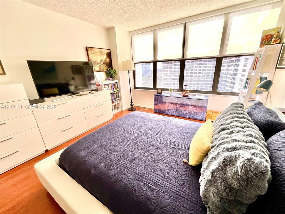 Floor-to-ceiling windows with multiple panes, wood-finish flooring, and neutral wall tones