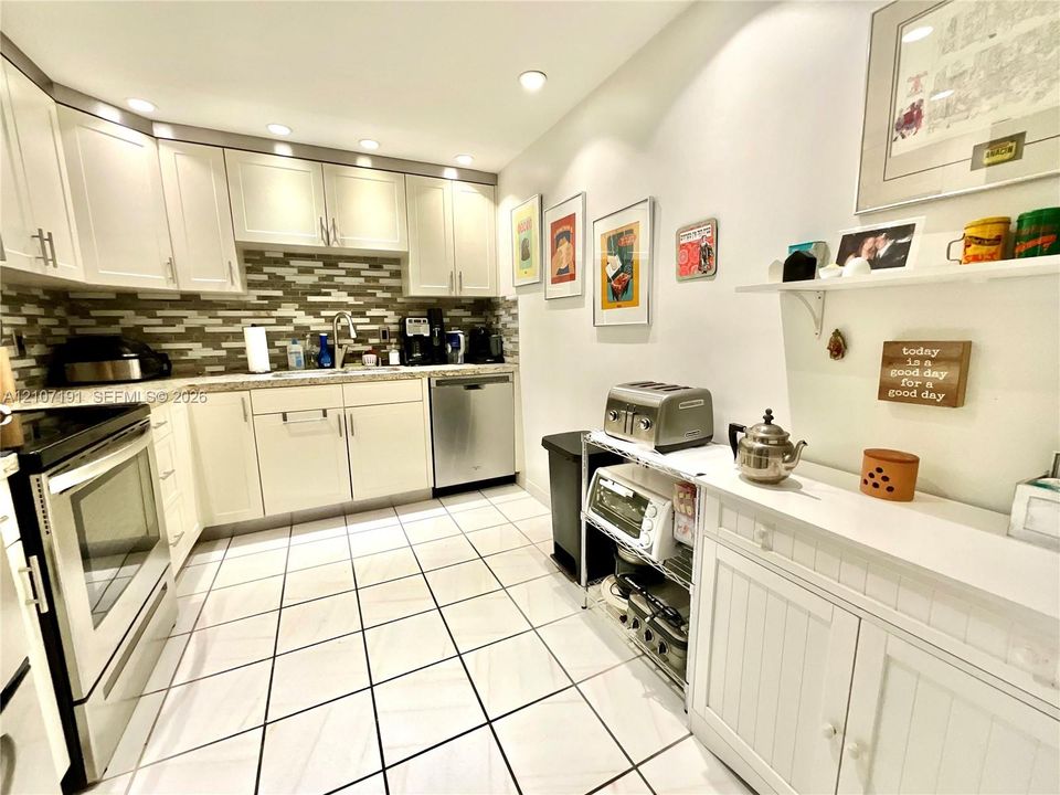 Kitchen featuring white cabinetry, stone-finish countertops, tile backsplash, stainless steel dishwasher, and ceramic tile flooring