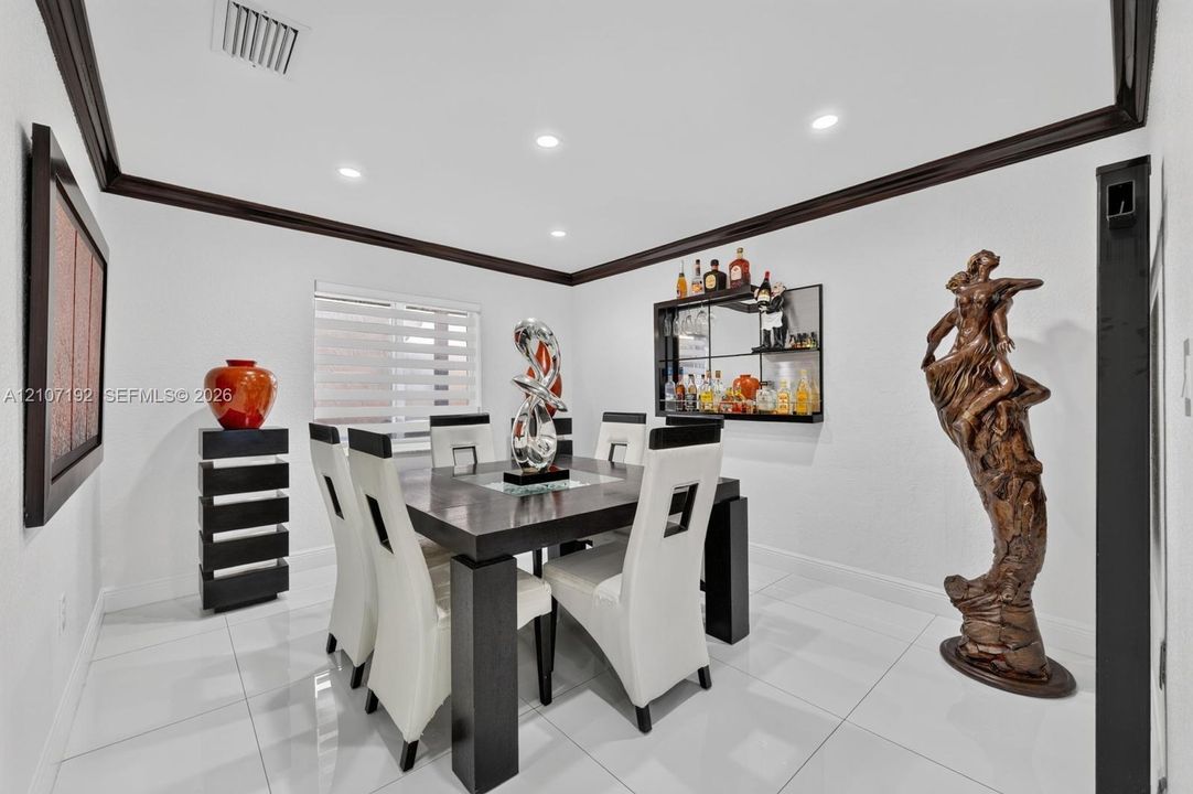 Large-format tile flooring, crown molding, recessed lighting, and built-in mirrored shelving