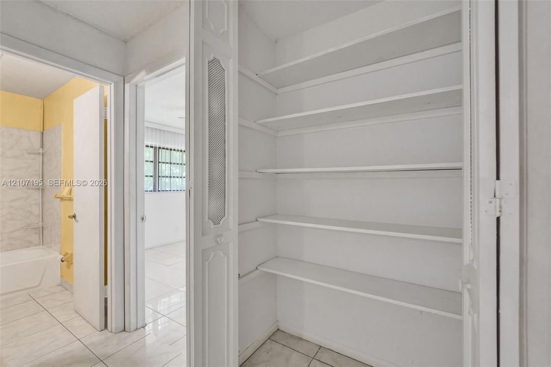 Built-in linen closet featuring multiple fixed shelving tiers and bi-fold doors with decorative inset detailing