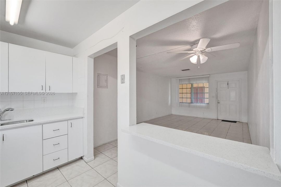 Kitchen featuring white cabinetry, a solid-surface pass-through counter, and ceramic tile flooring throughout the main area