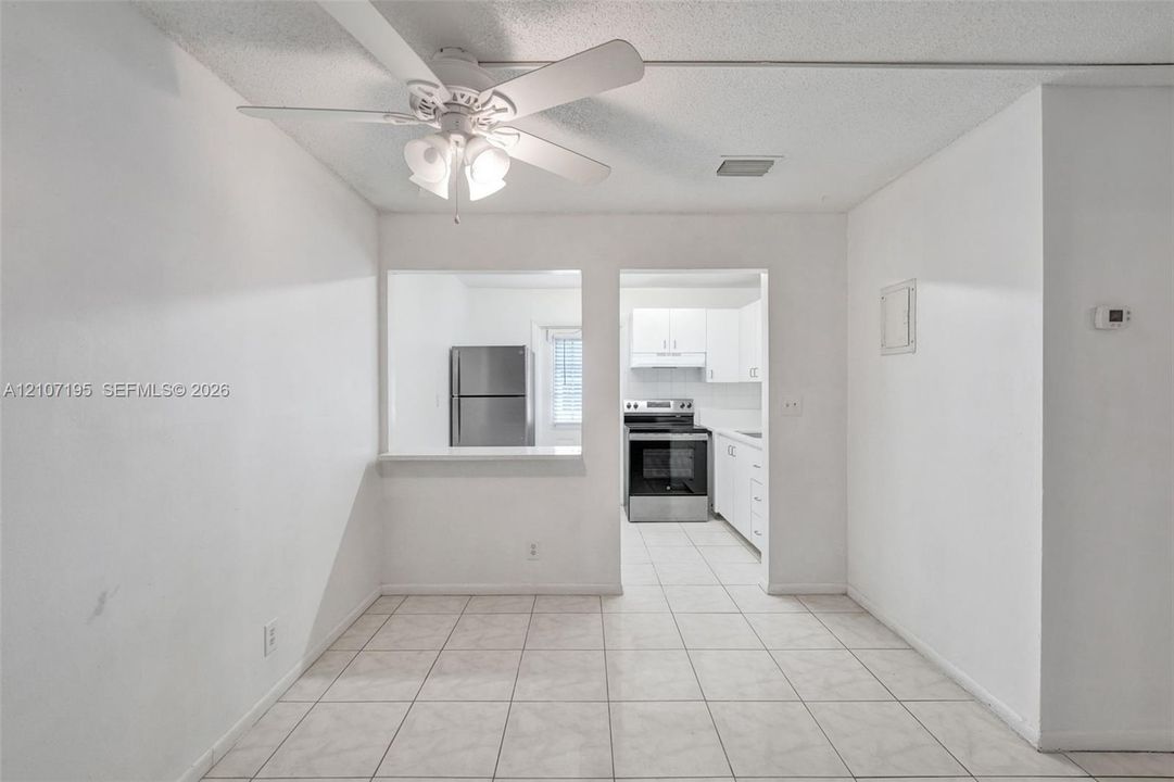 Ceramic tile flooring, white cabinetry, stainless steel kitchen appliances, and ceiling fan with integrated lighting