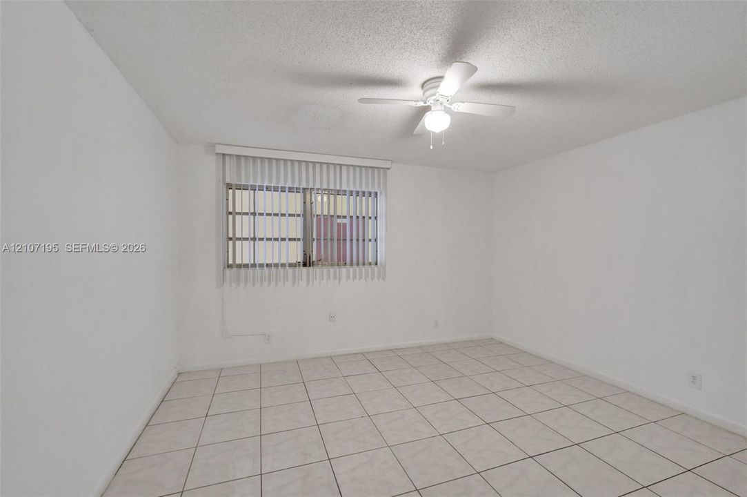 Neutral-toned tile flooring, ceiling fan with integrated lighting, and vertical window blinds