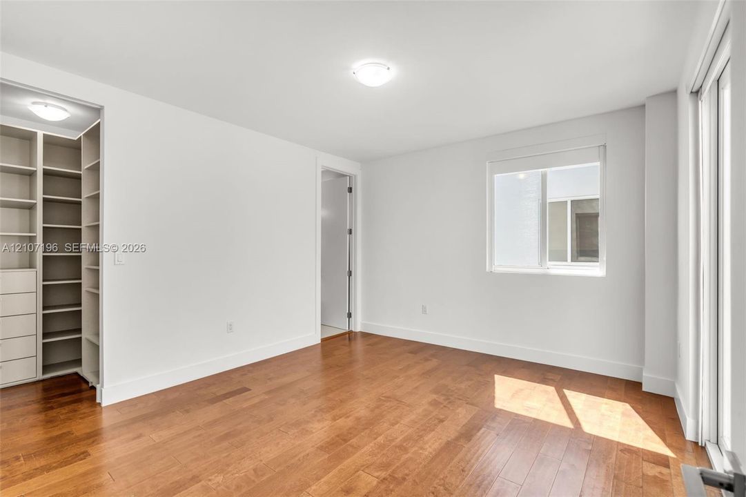 Interior room featuring wood-finish flooring, built-in shelving with integrated drawer storage, recessed ceiling lighting, and a single-pane window