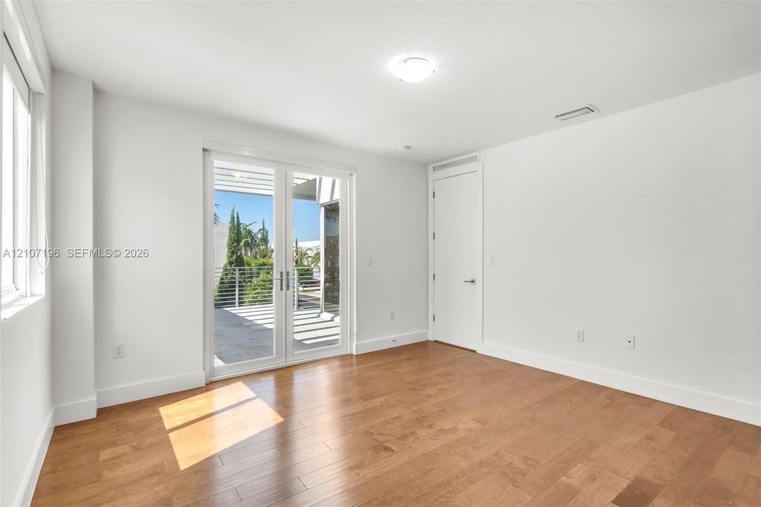 Interior space featuring wood-finish flooring, white walls, and glass-paned French doors opening to an exterior terrace