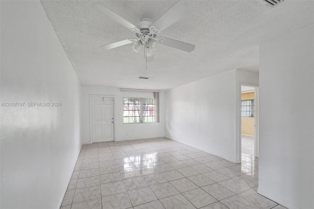 Interior space featuring tile flooring, a multi-blade ceiling fan with integrated lighting, and a multi-pane window