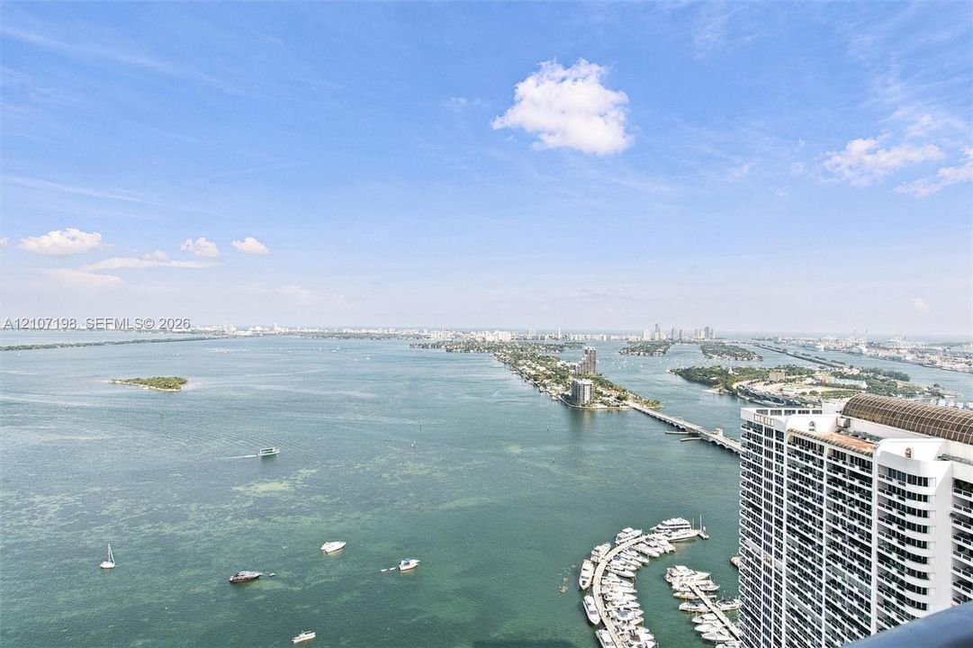High-rise perspective featuring expansive water panoramas, coastal horizon, and a protected marina with deep-water boat slips