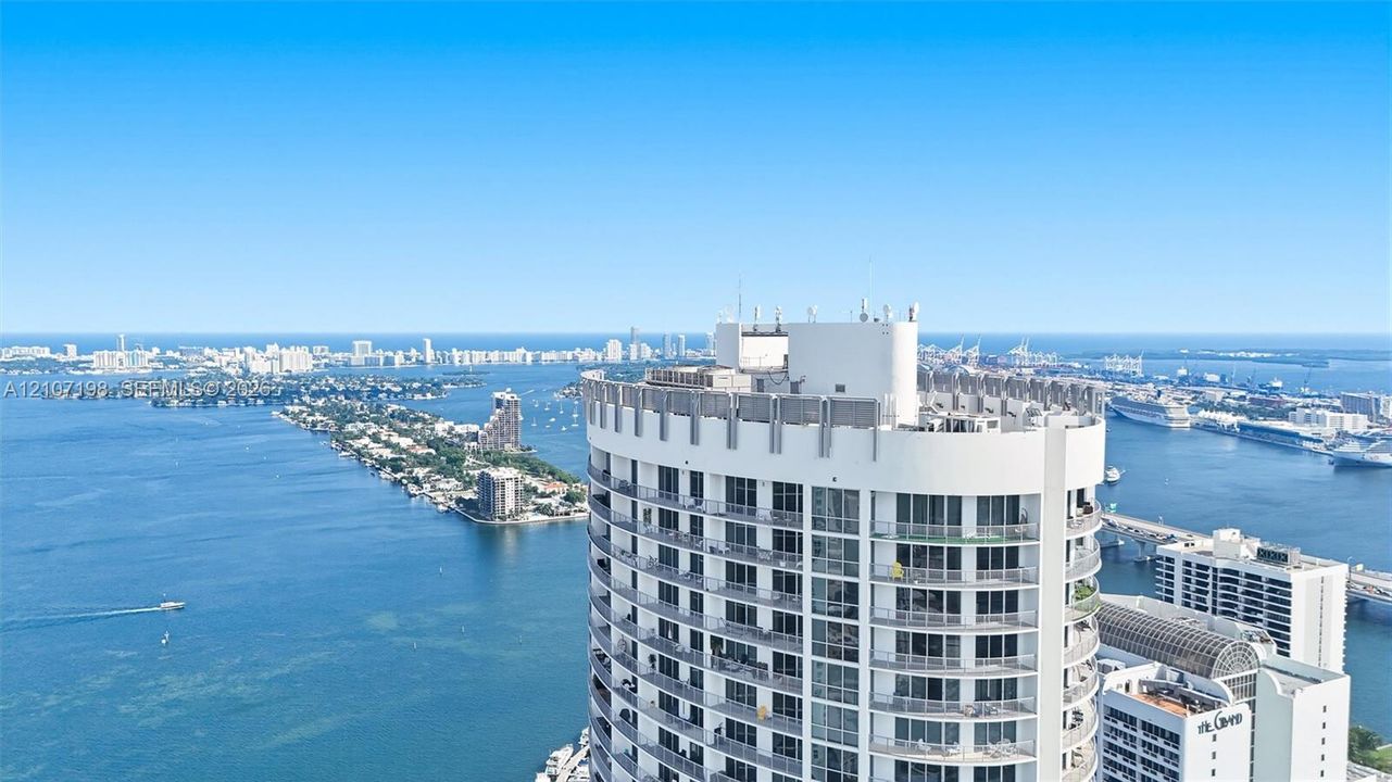 High-rise building featuring a curved architectural design, floor-to-ceiling glass windows, and private balconies overlooking the surrounding bay and coastal waterway