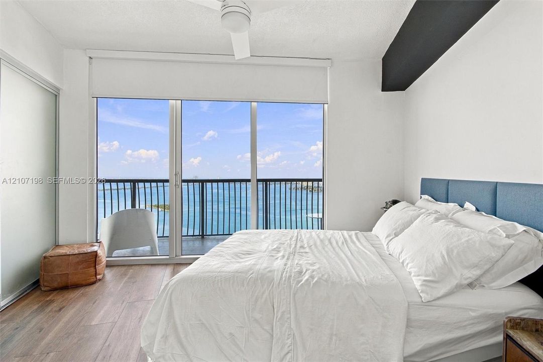 Floor-to-ceiling windows, wood-finish flooring, private balcony with metal railing, ceiling fan, and frosted glass door