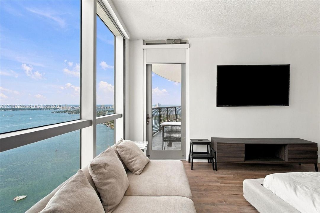 Floor-to-ceiling windows, wood-finish flooring, and direct access to an exterior balcony