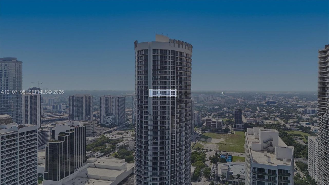 High-rise residential tower featuring a cylindrical glass facade, exterior balconies, and reinforced concrete structural elements