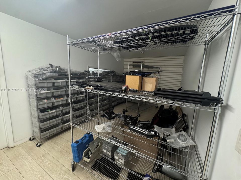 Storage space featuring wood-finish flooring and wall-mounted slatted storage paneling