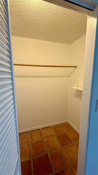 Closet featuring louvered bi-fold doors, clay tile flooring, and built-in rod and shelving