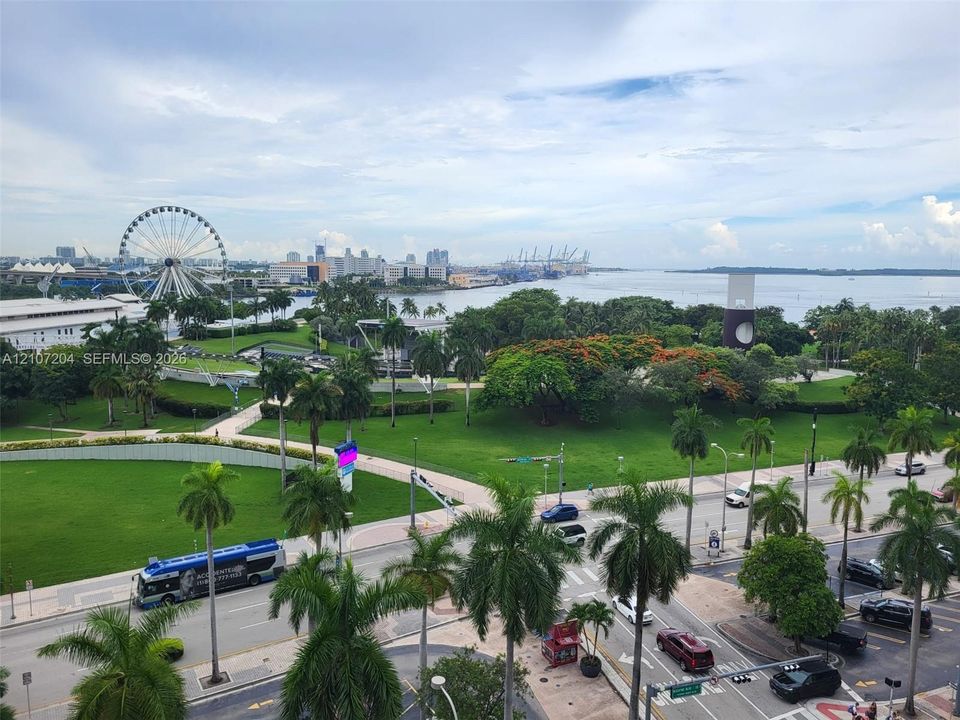 Elevated outdoor perspective featuring a panoramic outlook over a public park, waterfront, city skyline, and ferris wheel