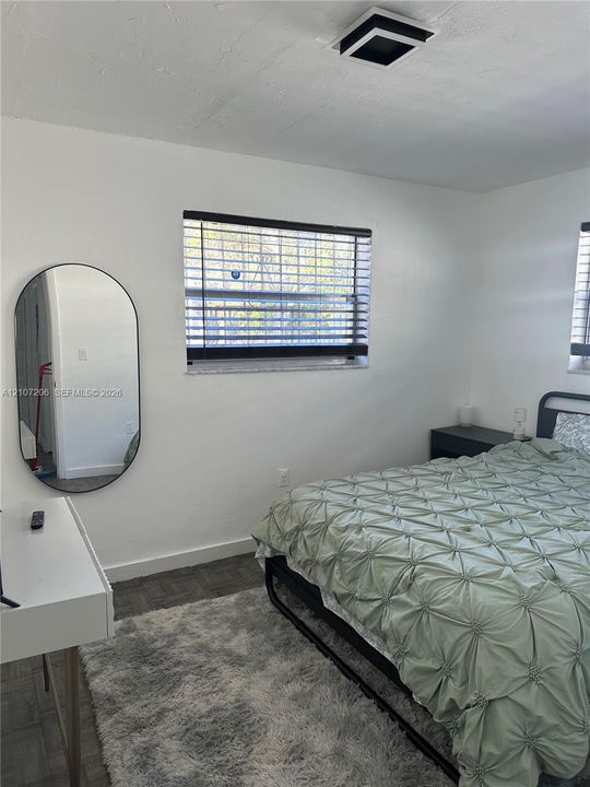 Neutral-toned interior featuring dark gray square-tile flooring, horizontal slat blinds, and a modern square flush-mount ceiling light fixture