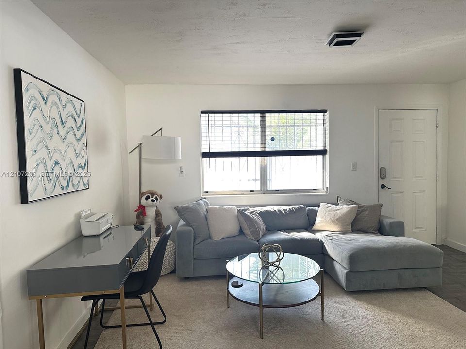 Neutral interior space featuring white walls, a multi-pane window with security bars, and a six-panel entry door