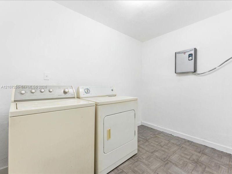 Dedicated laundry room featuring side-by-side washer and dryer appliances, tile flooring, and wall-mounted electrical panel for convenient utility access