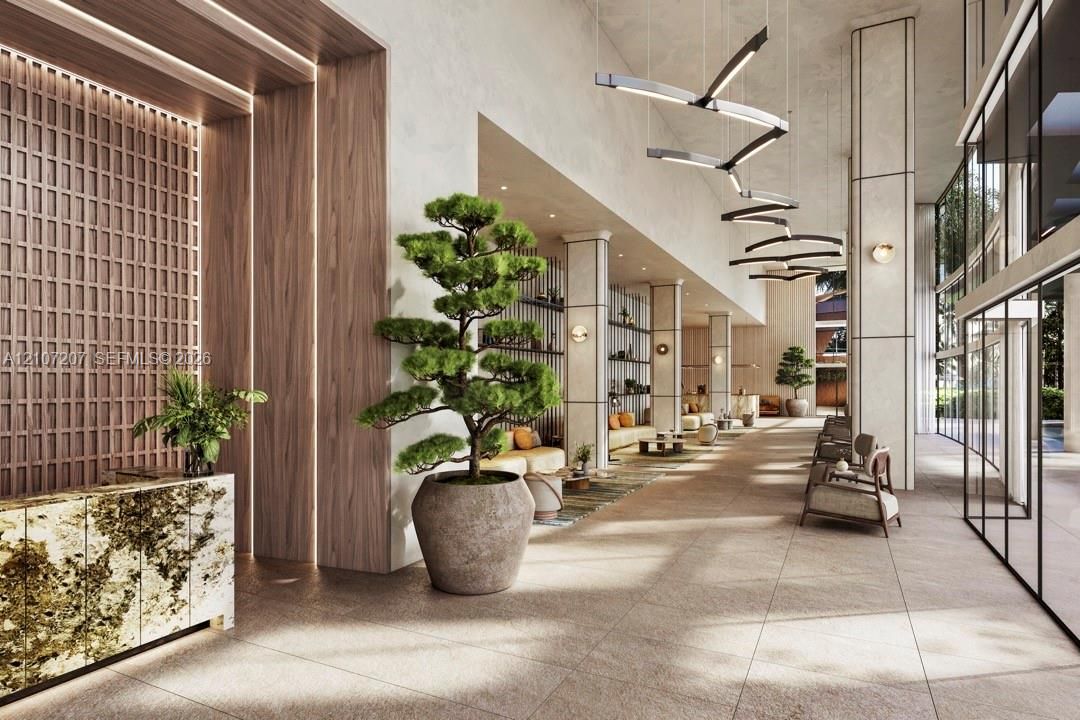 Grand lobby featuring high ceilings, stone tile flooring, geometric light fixtures, wood-paneled accent wall with integrated lighting, and a stone-clad reception desk
