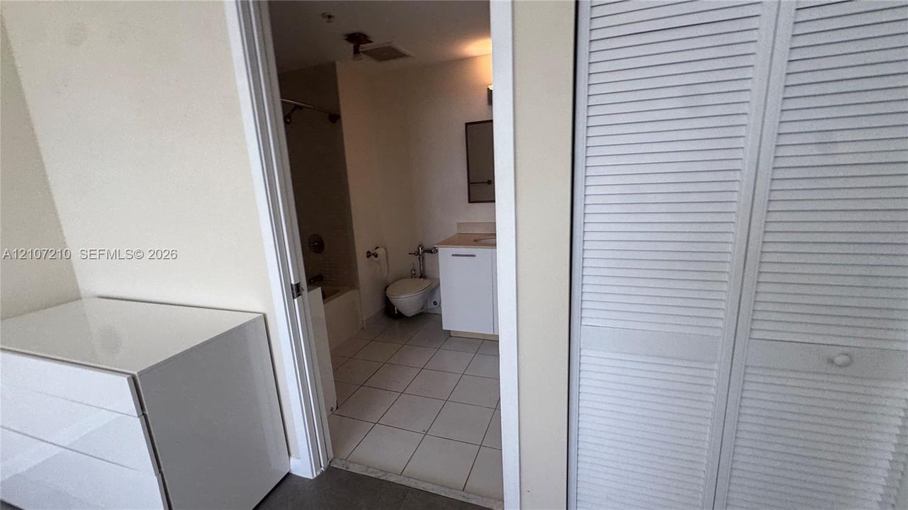 Bathroom featuring white floor tiling, vanity with a light-toned countertop, and bi-fold louvered closet doors