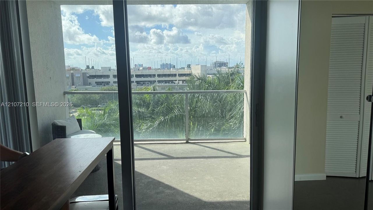Private balcony featuring a glass-panel railing, concrete flooring, and sliding glass door entry