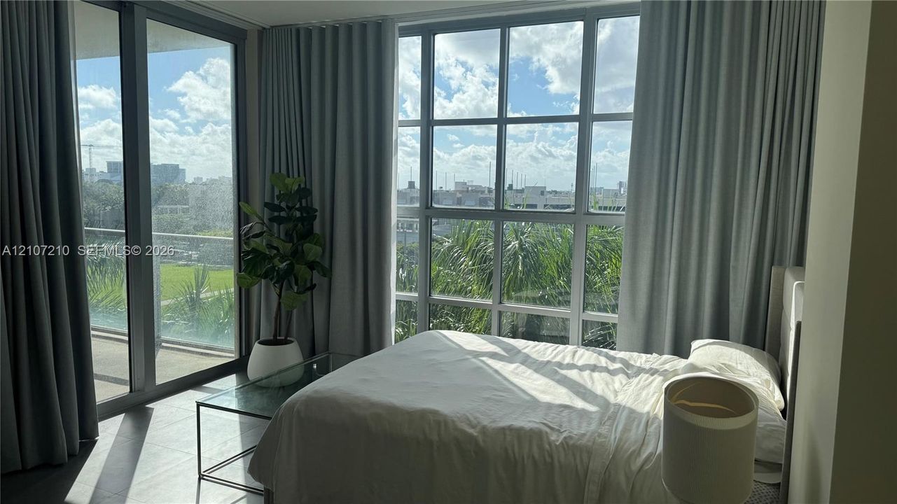 Floor-to-ceiling windows with grid detailing, tiled flooring, and a sliding glass door opening to a private balcony