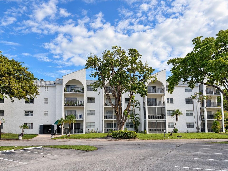 Multi-story building exterior featuring white stucco finish, arched architectural details, private recessed balconies, and shingled roofline