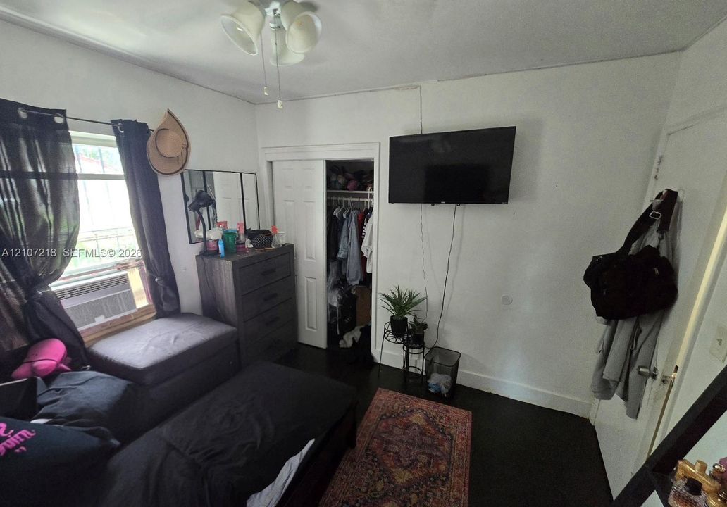 Room featuring dark wood-finish flooring, a built-in closet with sliding doors, and overhead lighting fixture