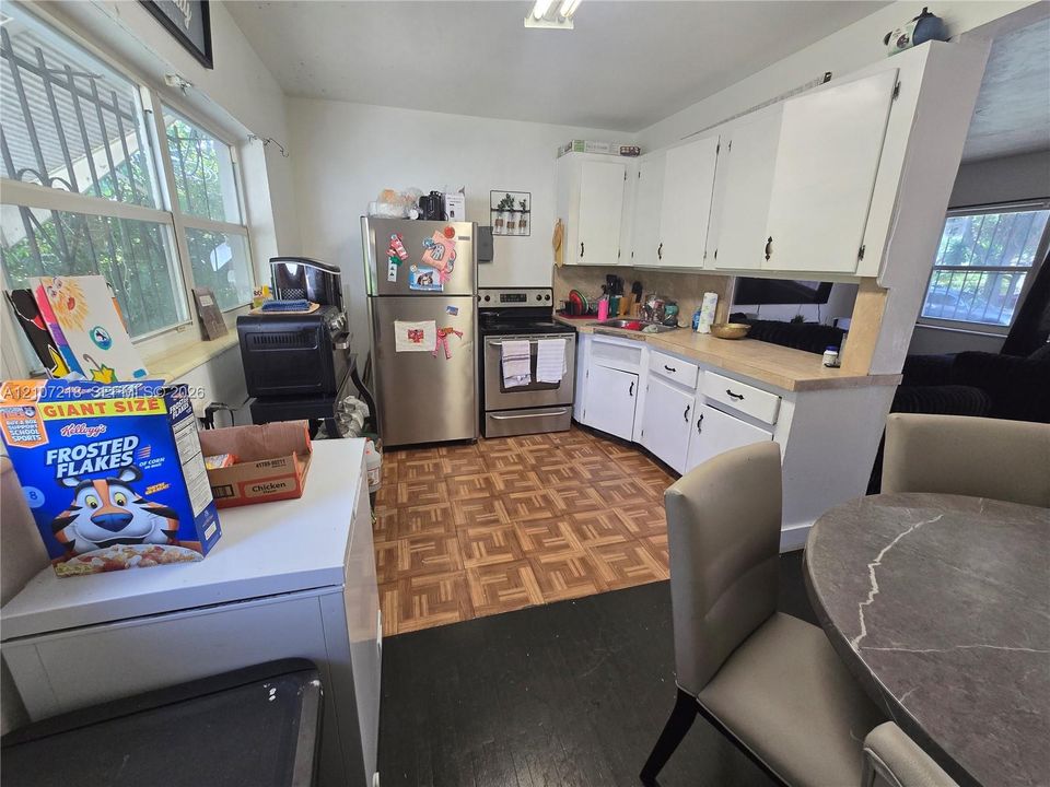Kitchen featuring white cabinetry, stainless steel appliances, butcher block countertops, and parquet flooring