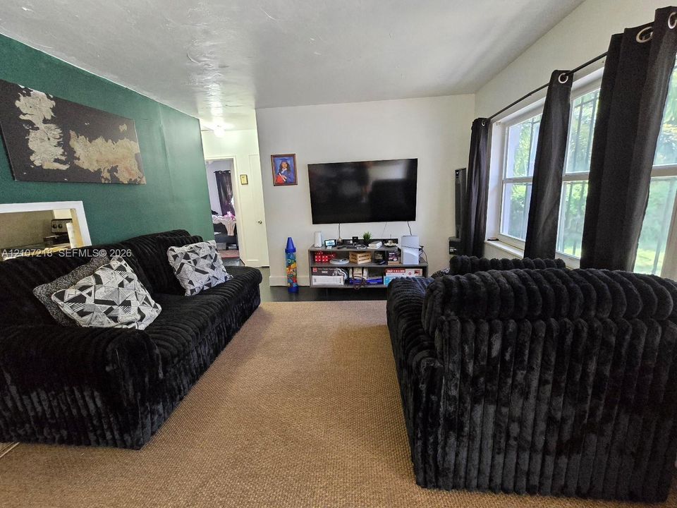 Living area featuring an accent wall, multi-pane window, and neutral wall-to-wall carpeting