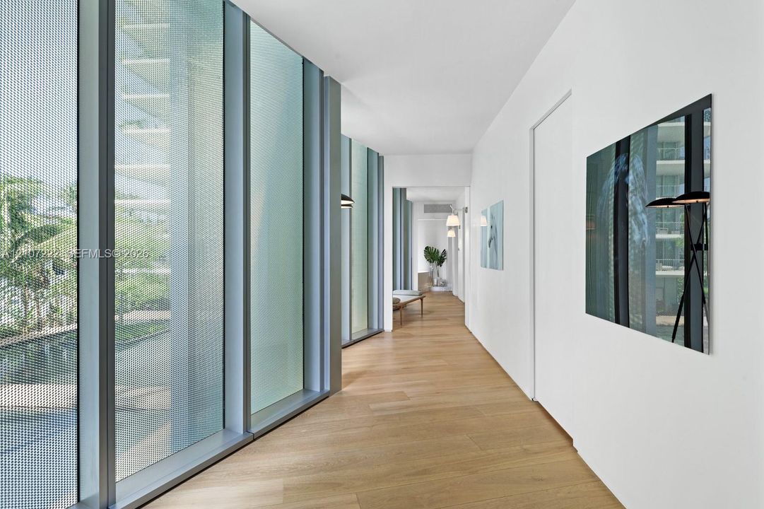 Floor-to-ceiling metal-framed windows, wood-finish flooring, and crisp white walls