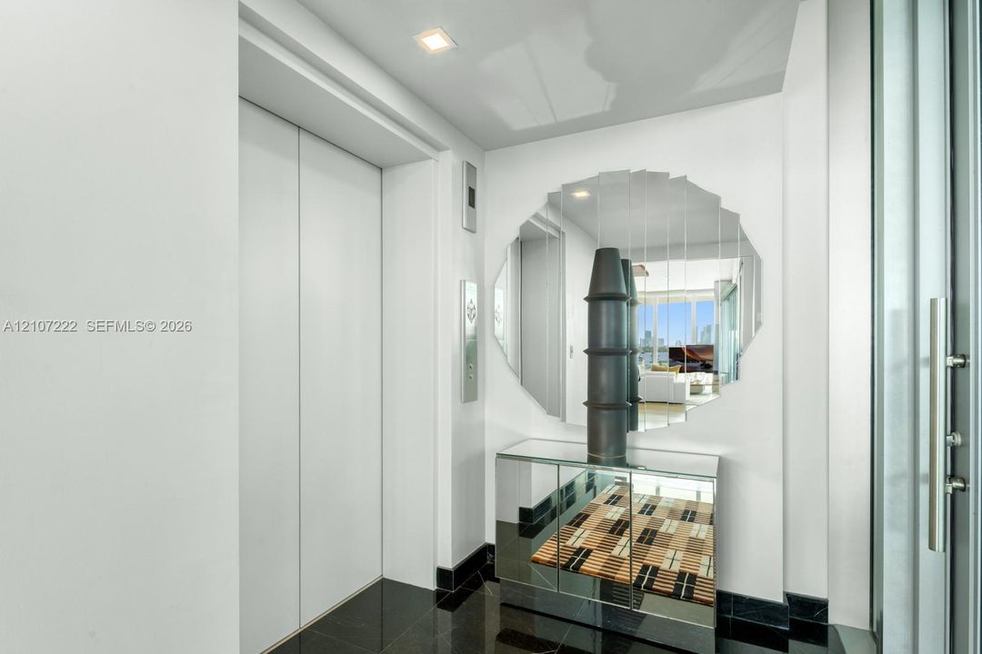 Private elevator entry with double-panel doors, high-gloss stone flooring, and recessed ceiling lighting