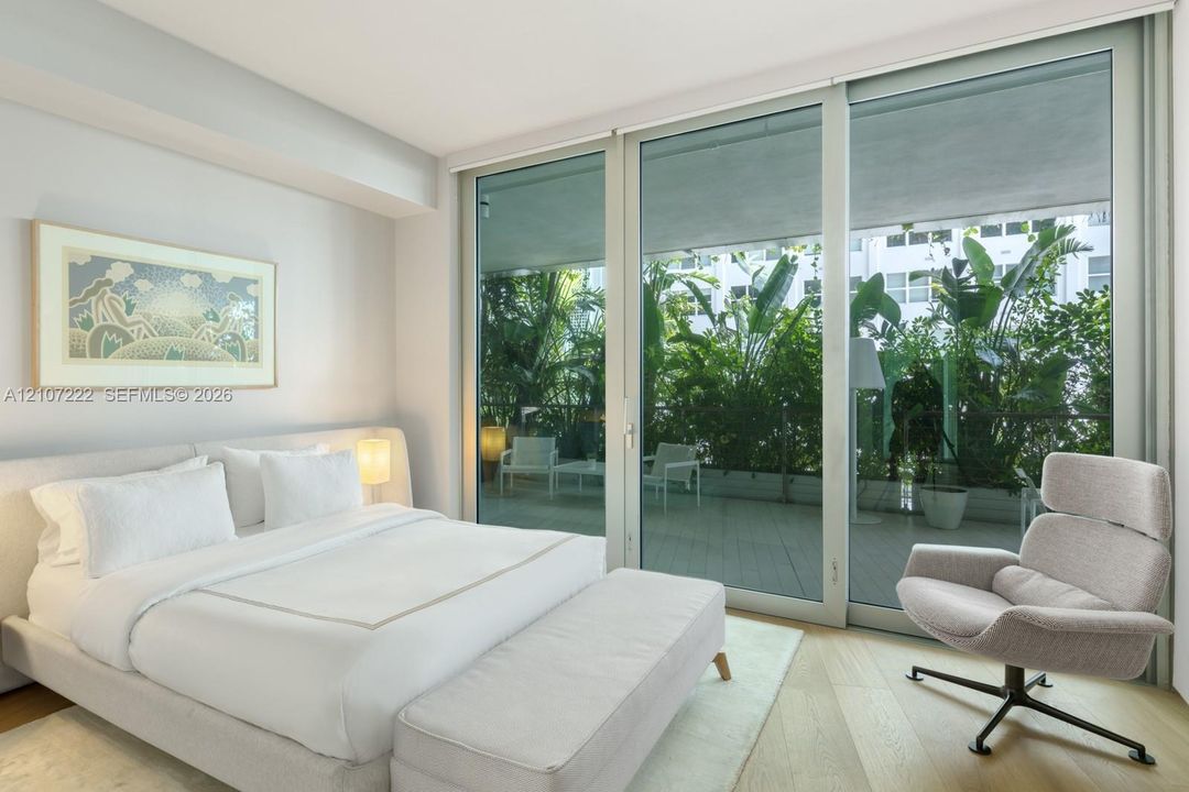 Floor-to-ceiling sliding glass doors, neutral wood-finish flooring, and expansive private balcony with perimeter railing