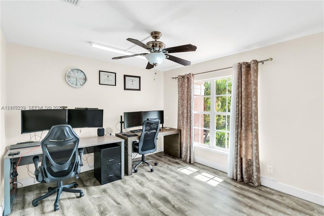 Room featuring wood-finish flooring, a multi-pane window with a curtain rod, and a ceiling fan with integrated lighting