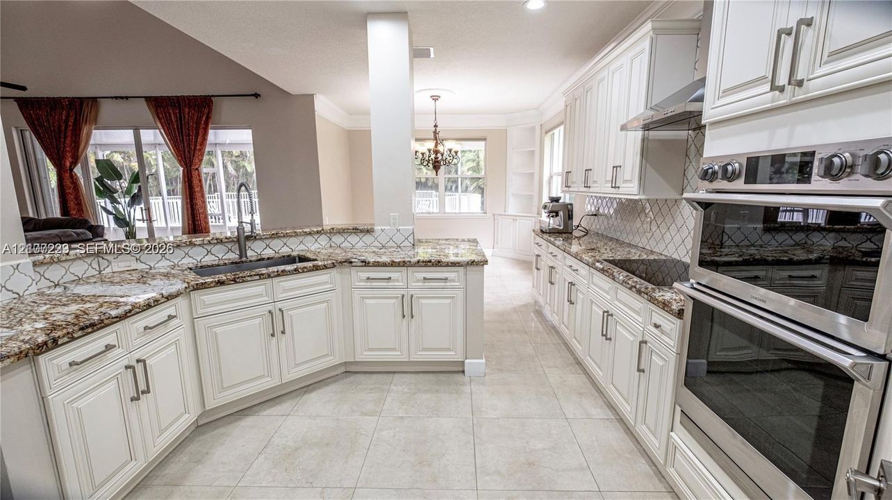Kitchen featuring white cabinetry, stone-finish countertops, tile backsplash, built-in double ovens, and tile flooring