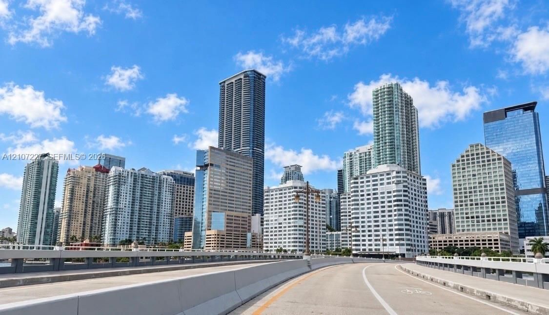 Urban thoroughfare featuring multi-story high-rise architecture, glass-paneled building facades, and concrete infrastructure