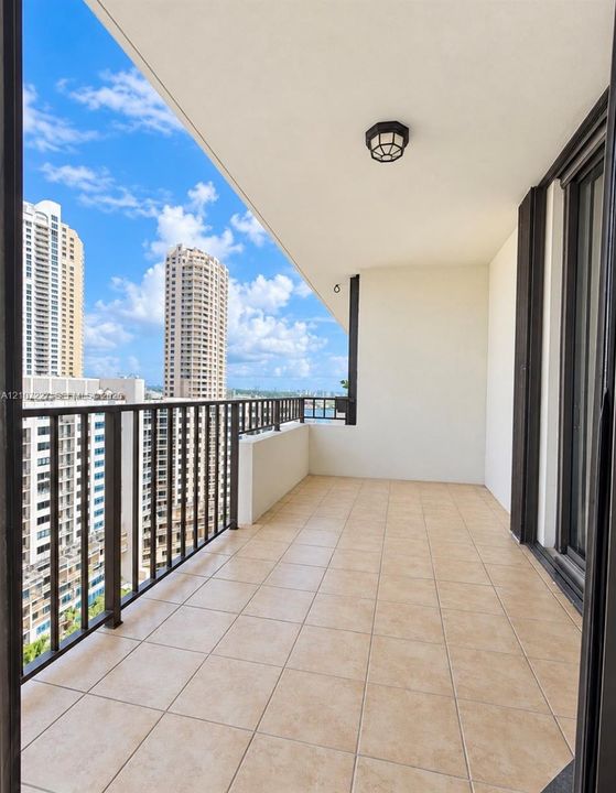 Covered balcony featuring tile flooring, metal railings, and a ceiling-mounted light fixture