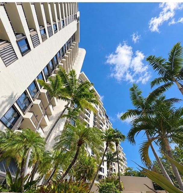 High-rise architectural exterior featuring tiered balconies, expansive glass windows, and mature palm trees
