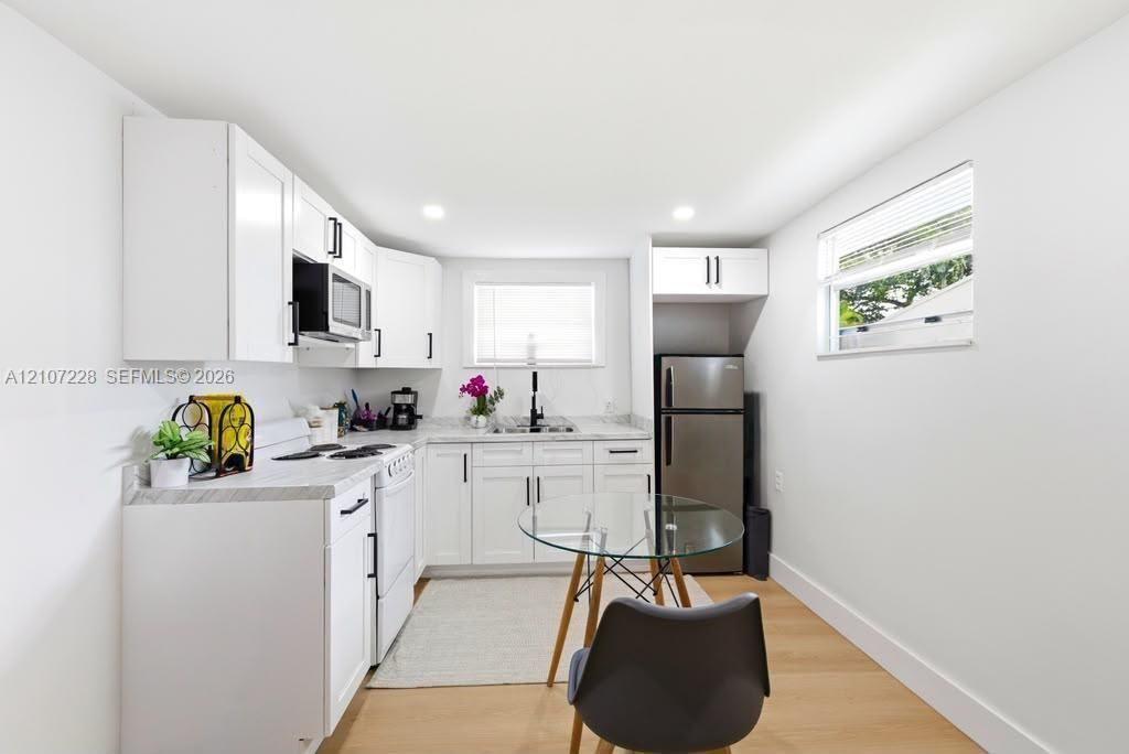 Kitchen featuring white shaker-style cabinetry, stone-finish countertops, stainless steel appliances, recessed lighting, and wood-finish flooring