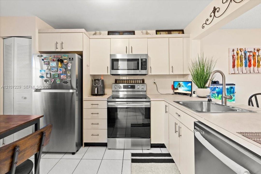 Kitchen featuring flat-panel cabinetry, stainless steel appliances, tile flooring, and a stainless steel undermount sink with a gooseneck faucet