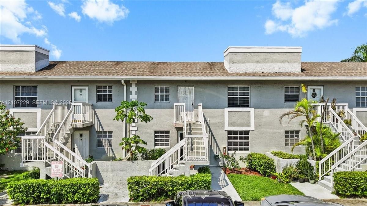 Multi-level exterior featuring a stucco facade, external staircases with white railings, and grid-patterned windows