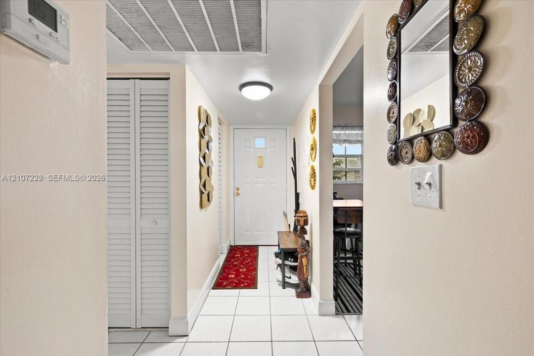 Entryway featuring white tile flooring, flush-mount ceiling lighting, and a white paneled front door with a glass insert