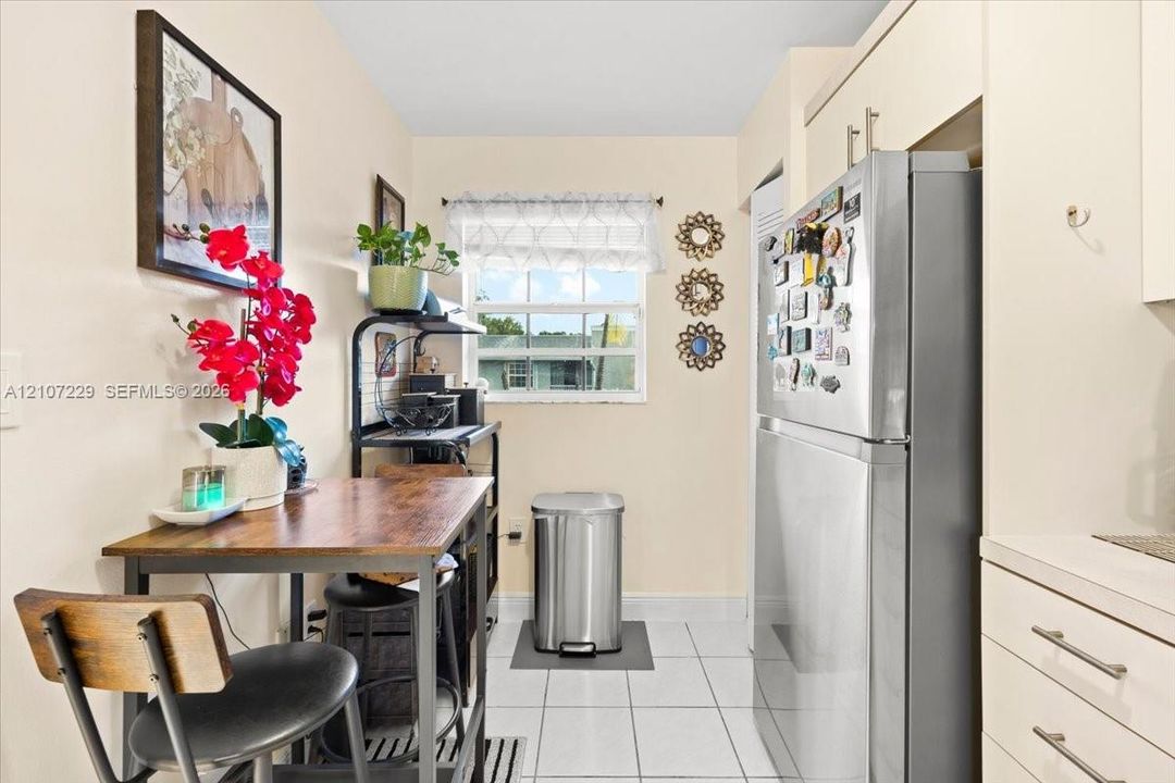 Kitchen featuring ceramic tile flooring, built-in cabinetry with stainless steel pulls, and a window with a sash frame