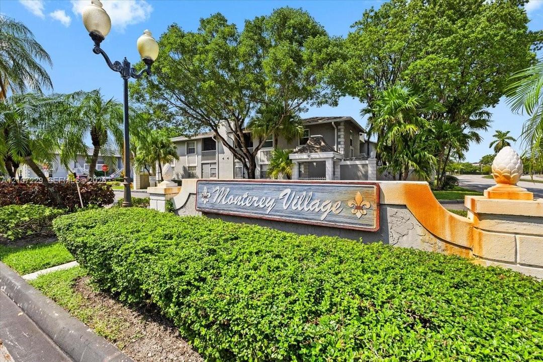 Stone-finish entrance monument featuring decorative finials and manicured landscaping, illuminated by a multi-head lamp post