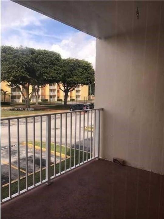 Covered balcony featuring concrete flooring and a white metal railing