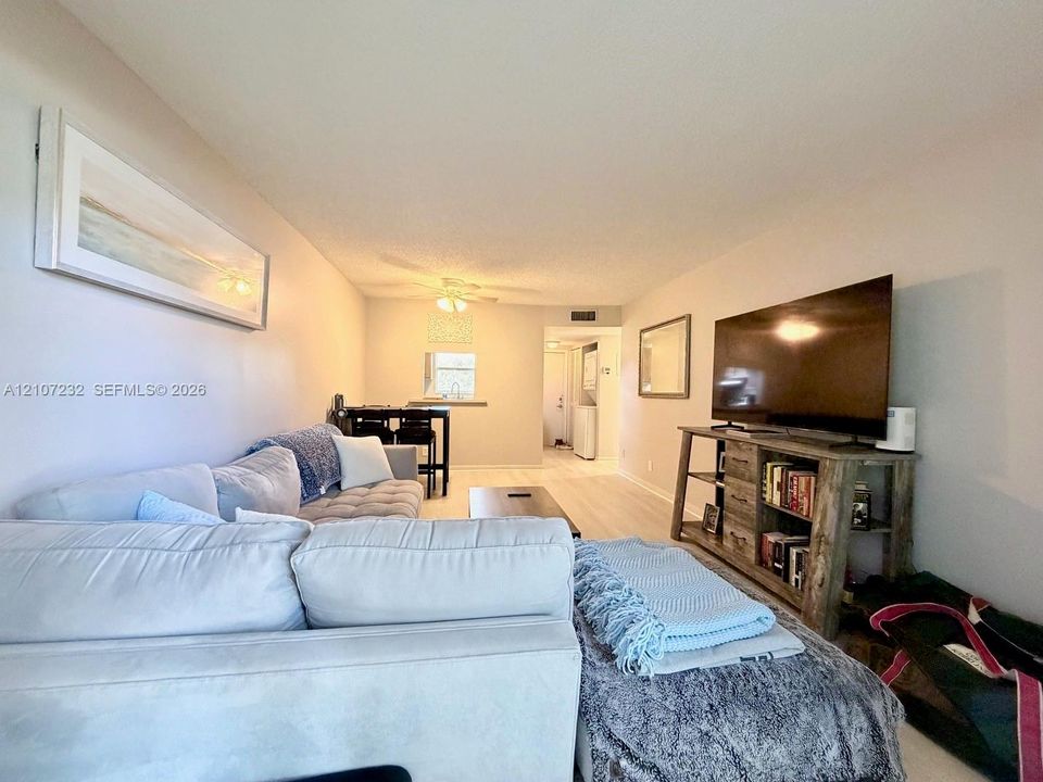 Open-concept interior featuring neutral wall tones, light wood-finish flooring, and a ceiling-mounted light fixture