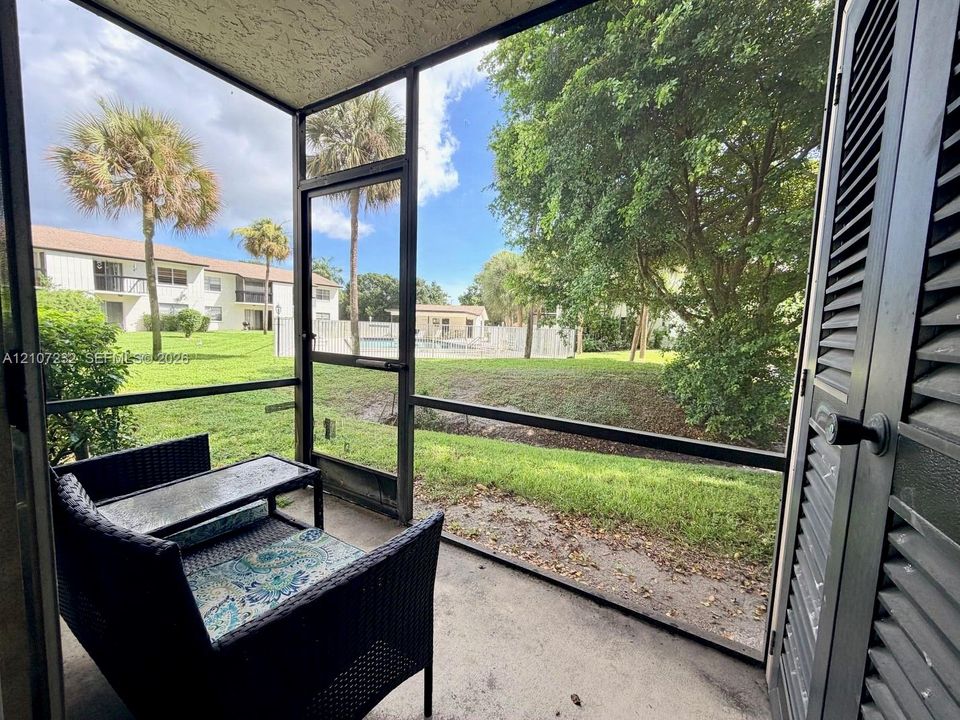Screened-in patio with concrete flooring, louvered utility closet door, and metal frame enclosure