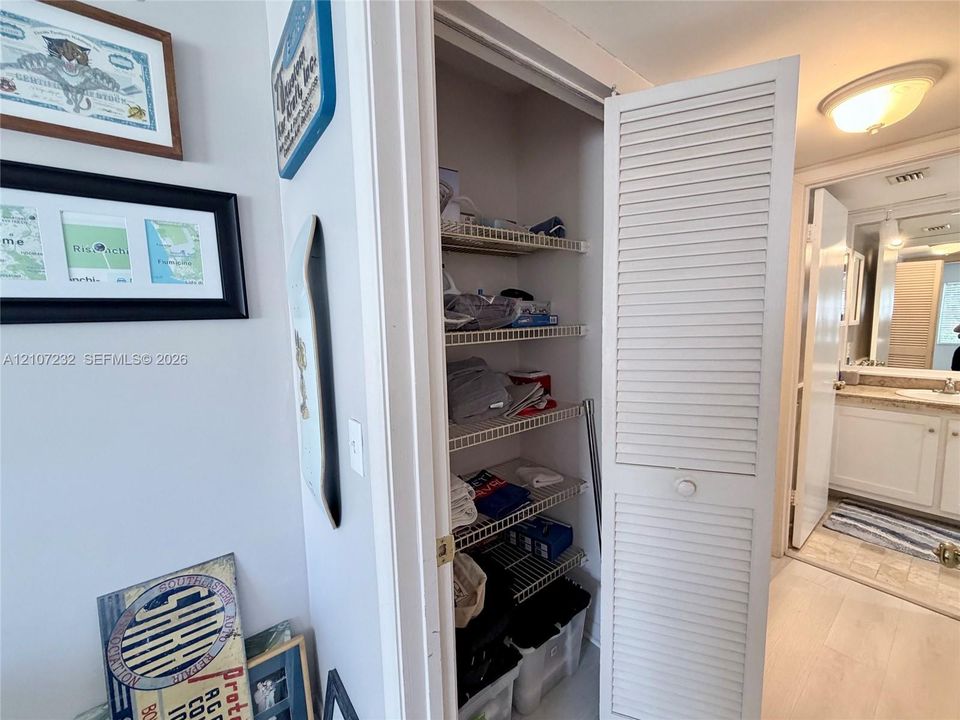 Storage closet featuring white louvered doors and multi-tier wire shelving