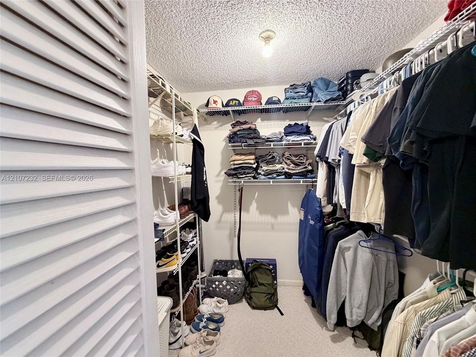 Storage space featuring white louvered doors, multi-level wire shelving, and overhead lighting