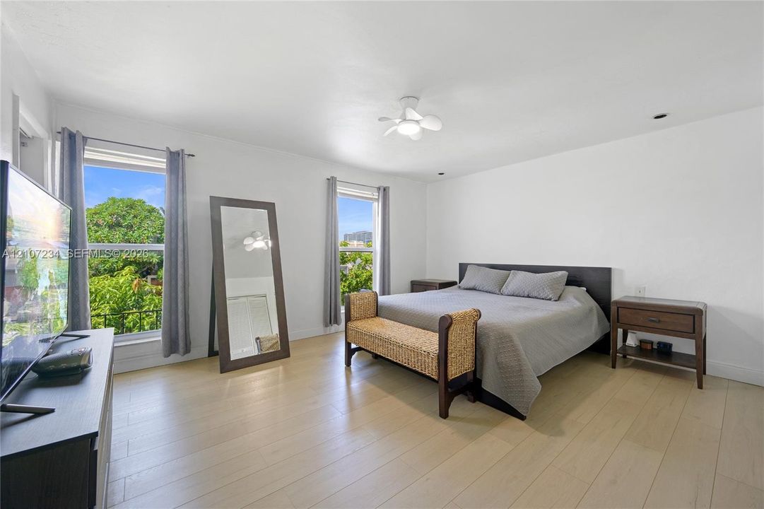 Neutral interior space featuring wood-finish flooring, dual windows, and a ceiling-mounted light fixture